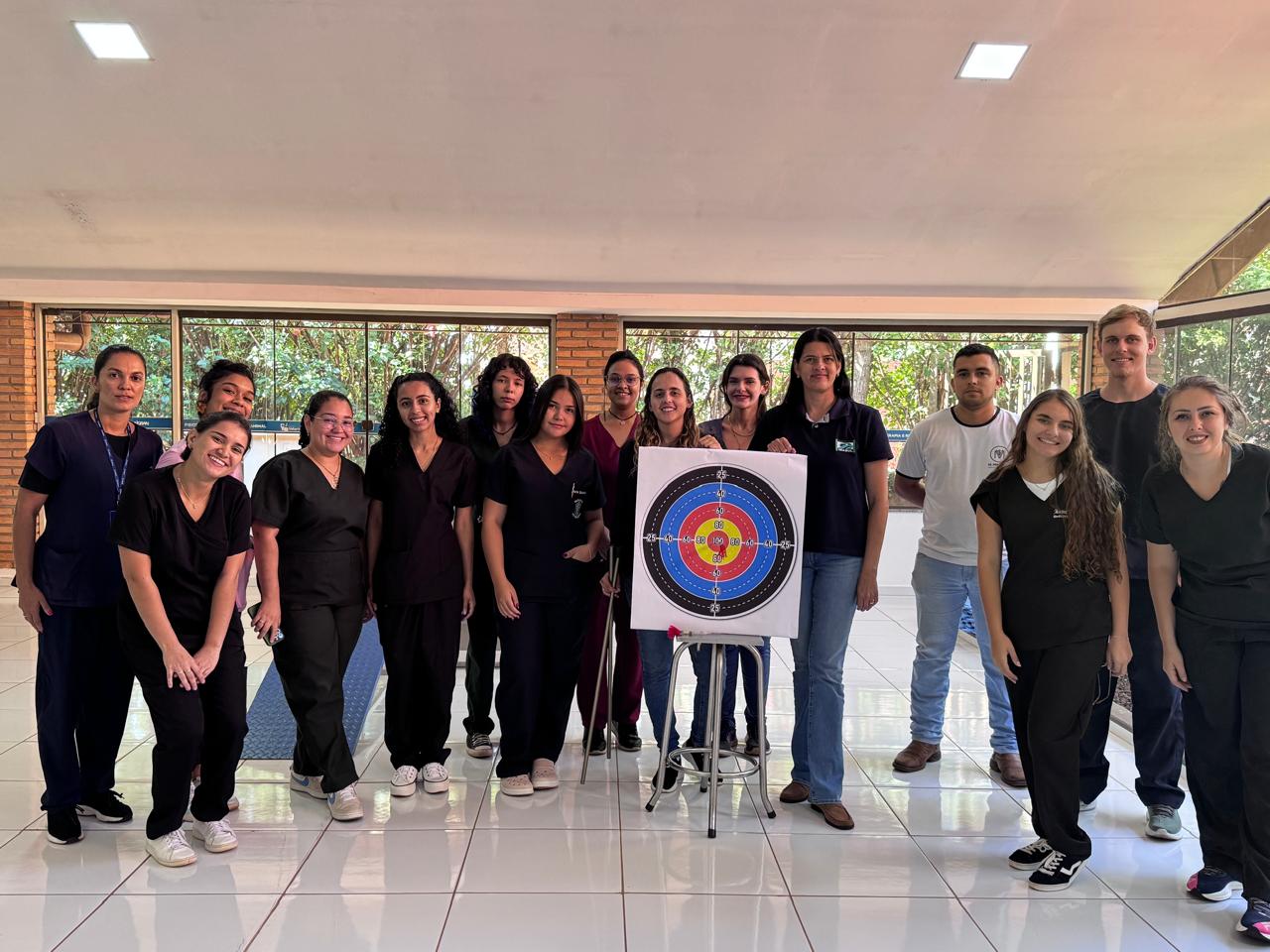Foto mostra a equipe do CRAS/Imasul reunida durante a XVI Semana Científica de Medicina Veterinária. O grupo, formado por homens e mulheres, posa em um espaço interno ao lado de um alvo de arco e flecha, sorrindo para a câmera. A maioria veste uniforme escuro, em clima de integração e atividade científica.